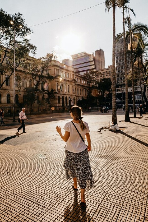 Woman Walking a Palm-Lined City Square at Golden Hour