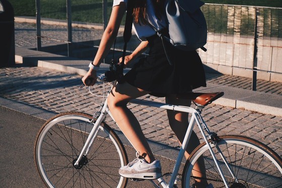 Person cycling on a cobblestone path with a backpack